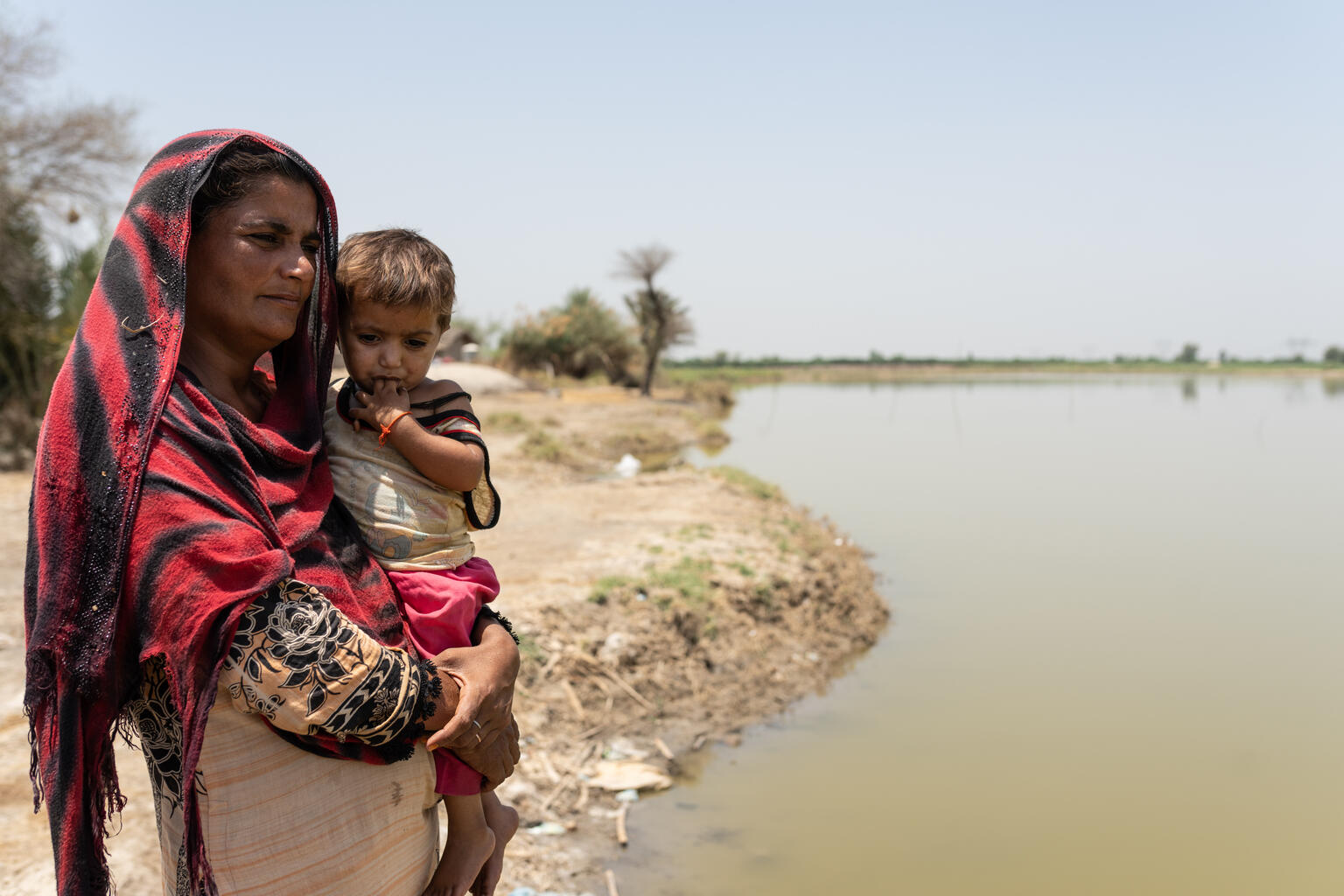 Benazir, 30, stands with her daughter, Oumara, 3, next to stagnant water that still remains more than 6 months after the devastating floods of 2022.